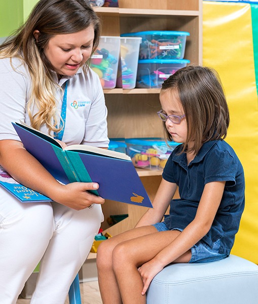 Heath care provider sitting and reading to child sitting covenant care