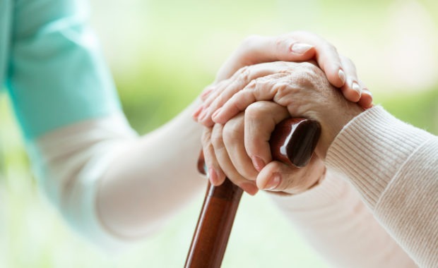 Nurse comforting elder lady holding a cane by touching her hands. Covenant Care