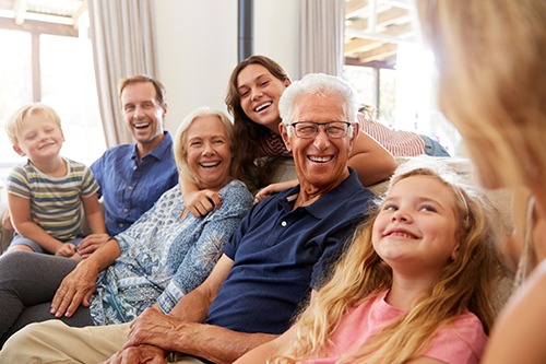 Multi-Generation Family Sitting On Sofa Relaxing And Chatting. Covenant Care