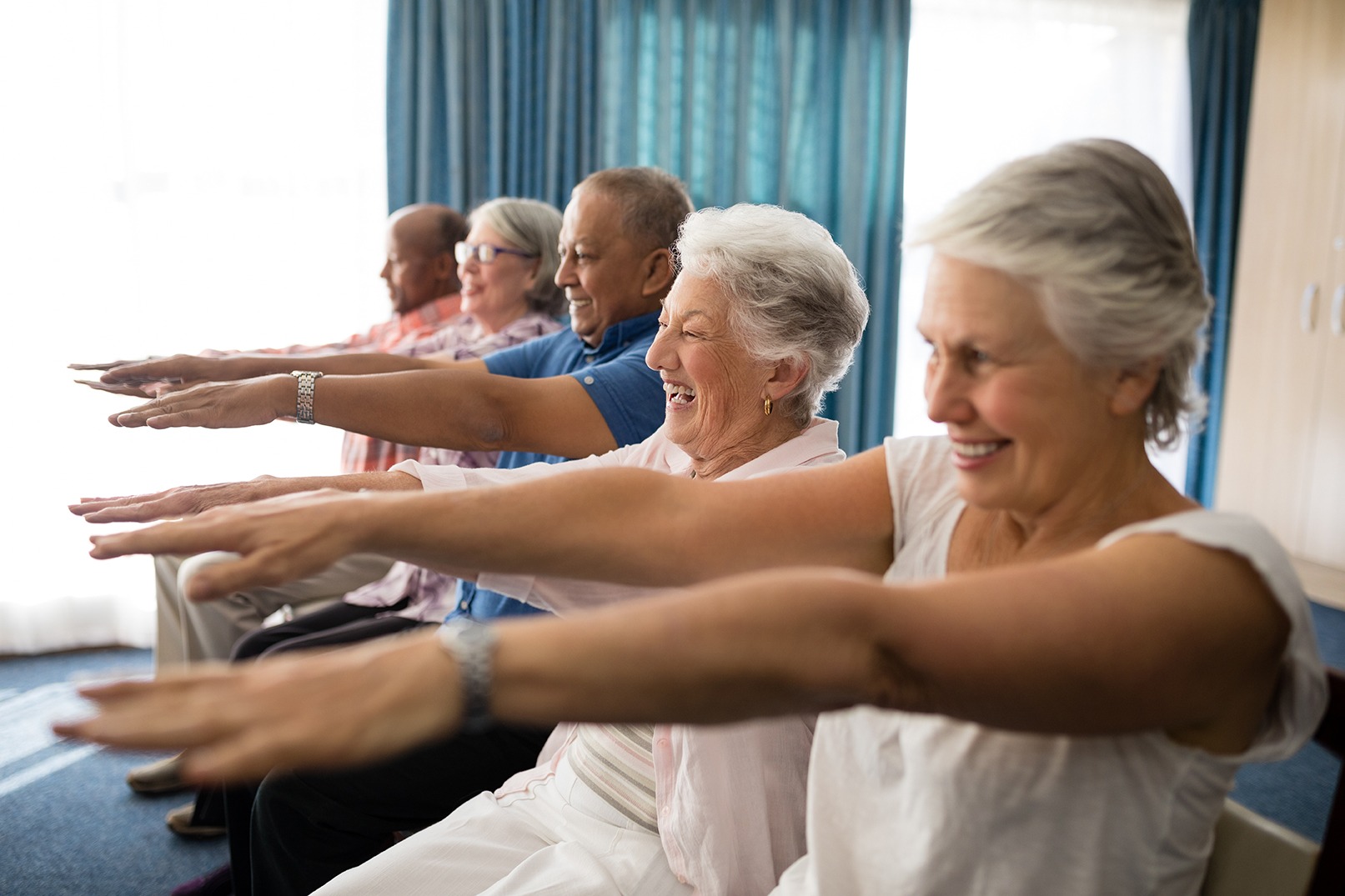 Cheerful senior people exercising with arms raised. Covenant Care